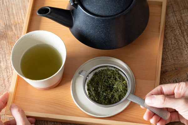 燕三条 ハンドル付き茶こし なごみ槌目 抹茶対応 日本製 日本 現行品 木のトレイの上でカップにのせた茶こしに急須からお茶を注ぐ俯瞰イメージ