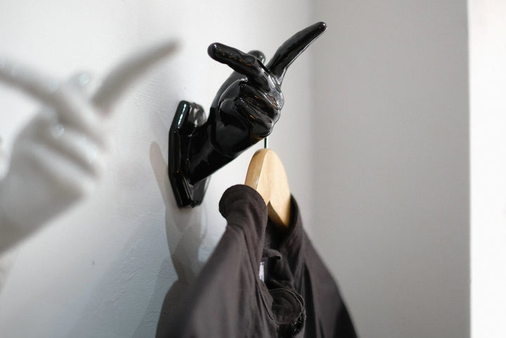 フレミングの手を模した黒い陶器のオブジェ。左手の形が白い壁にとり付けられている。親指には服が掛かったハンガーが掛かっている。